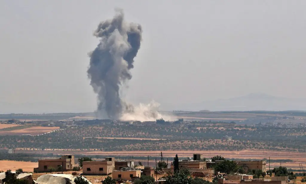 Smoke billows above buildings during a reported air strike by the Syrian army on Khan Sheikhun on Monday