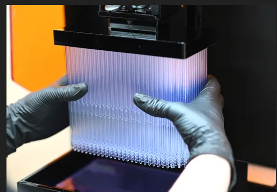 Jason Spurlock, process control engineer for Envision TEC, removes 400 flexible nasal swabs made with a 3D printer in Dearborn. -Photo: Max Ortiz, The Detroit News