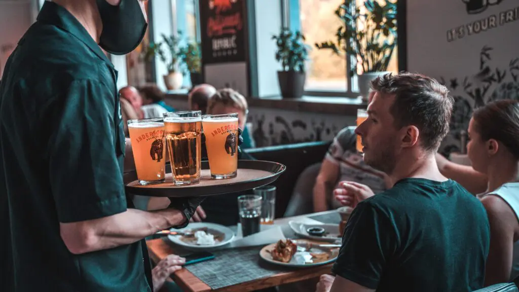A waiter wearing a face mask serves food to restaurant customers