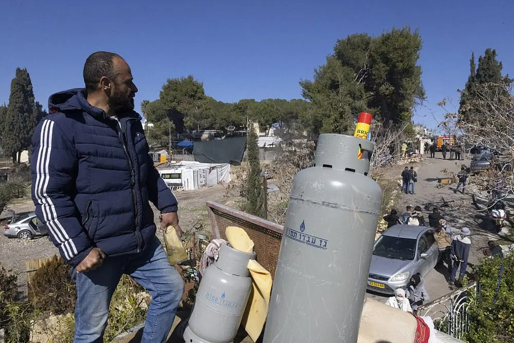 Mahmoud Salhiyeh stands on the roof of his home with gas canisters, just before he and his family were due to be forcibly expelled, Sheikh Jarrah, East Jerusalem, Jan. 17. Photo: Oren Ziv/Activestills.org