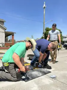 Dearborn Department of Public Works employees install a rubber speed hump on Hemlock St, between Calhoun and Bingham, as part of a comprehensive effort to curb speeding and reckless driving in Dearborn neighborhoods. - Photo courtesy of Dearborn Department of Communications.
