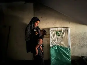 A displaced Palestinian woman helps her son drink milk at a school classroom where she shelters, amid food scarcity, as Israel-Hamas conflict continues, in Khan Younis in the southern Gaza Strip, June 26, 2024. – Photo by Reuters