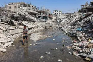 A boy walks through a puddle of sewage water past mounds of trash and rubble along a street in the Jabalia camp for Palestinian refugees, in the northern Gaza Strip – File photo