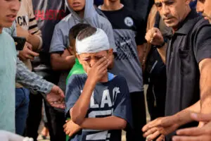 Injured Palestinian child, Yousef Al-Bayouk, weeps over his brothers, Moath and Moataz, who were killed in Israeli strikes, as mourners attend their funeral, at Nasser hospital in Khan Younis. southern Gaza Strip, May 15, – Photo by Reuters