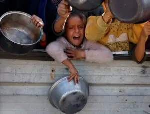 Palestinians gather to receive food cooked by a charity kitchen, amid a hunger crisis, as the Israel-Gaza conflict continues, in Khan Younis in the southern Gaza Strip, December 4, 2024