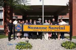 Suzzane Sareini standing with her children and granchildren and relatives behind the sign of the senior building that bares her name. 