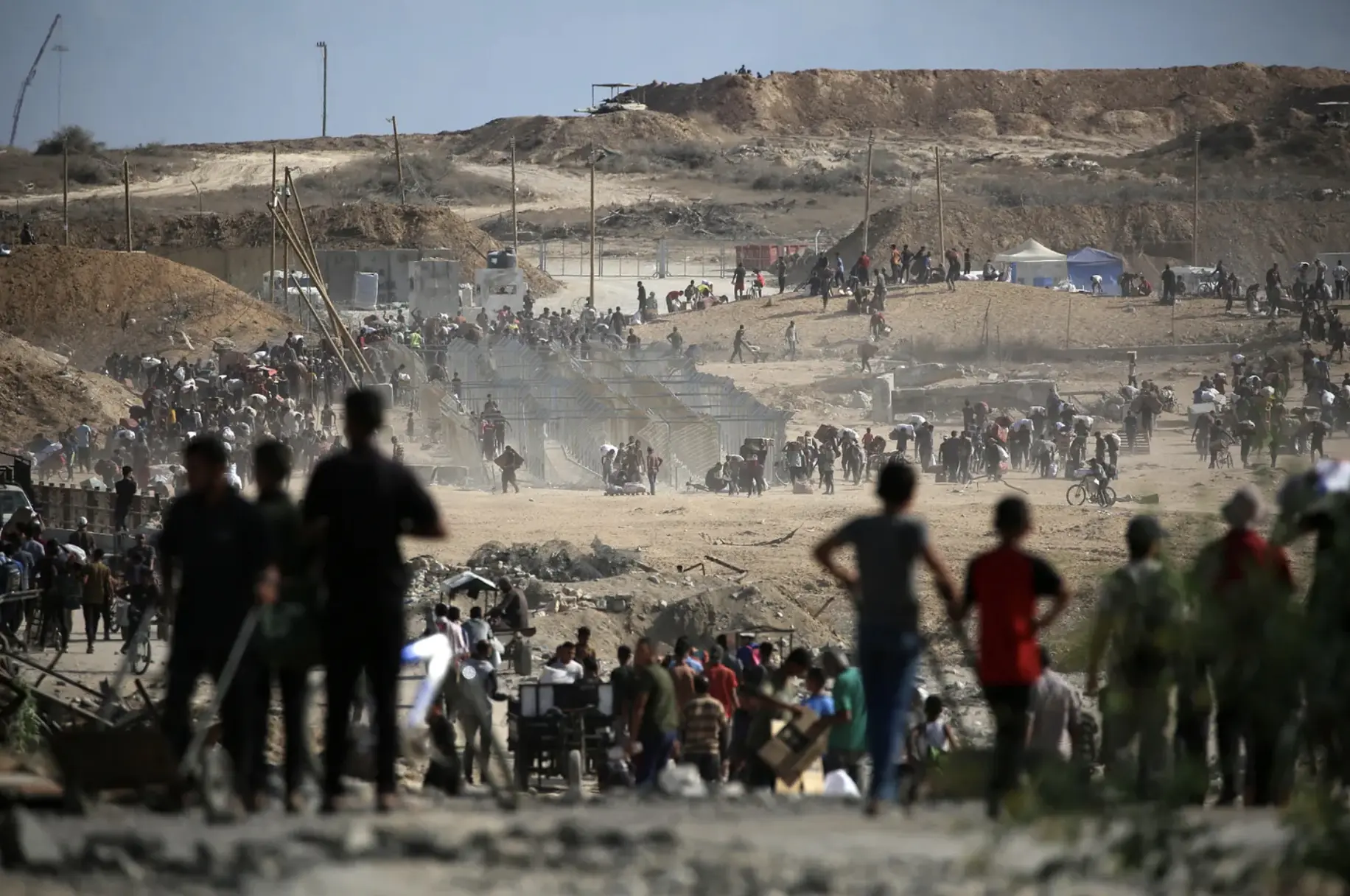 Palestinians carrying bags return from a food distribution point run by the Gaza Humanitarian Foundation near the Netzarim corridor in the central Gaza Strip on October 5, 2025.