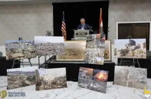 Wayne County Commissioner Sam Baydoun speaks at the gathering and infront of the podium pictures of some of the destroyed homes during the Israeli invasion of south lebanon. – Photo by Dearborn.org