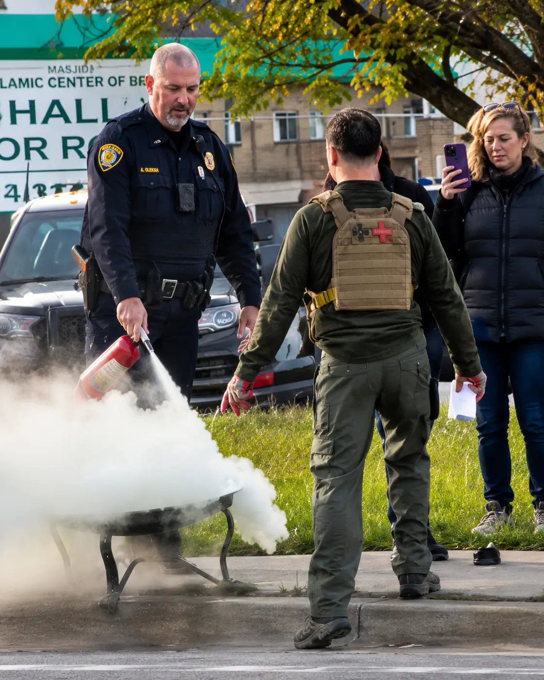 Dearborn police officer distinguishes the burning Holy Quran by Anti-Muslim agitator Jake Lang near the Islamic Center of America on Ford Road in Dearborn on May 11. – Photo via video grab