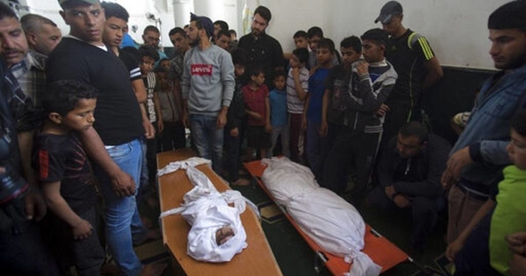 Palestinians stand around the bodies of a four-months-old girl Maria Al-Ghazali, her father Ahmad and mother Iman Al-Ghazali, laid inside a coffin, who were killed in a late Sunday Israeli missile strike during their funeral in town of Beit Lahiya, northern Gaza Strip, Monday, May. 6, 2019. AP