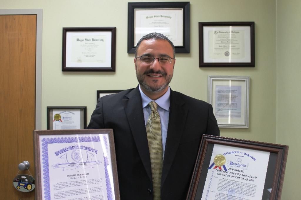 Youssef Mosallam holding certificates of recognition for his academic work in Dearborn Public Schools