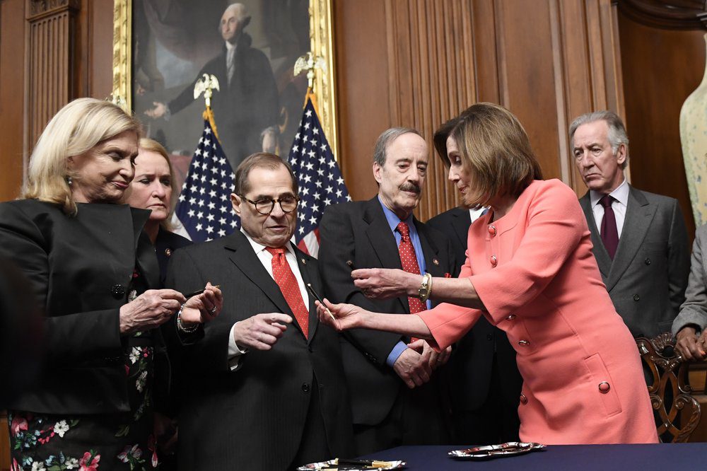 Speaker Pelosi hands out pens after she signs a resolution to transmit the two article of impeachment to the Senate on Wednesday
