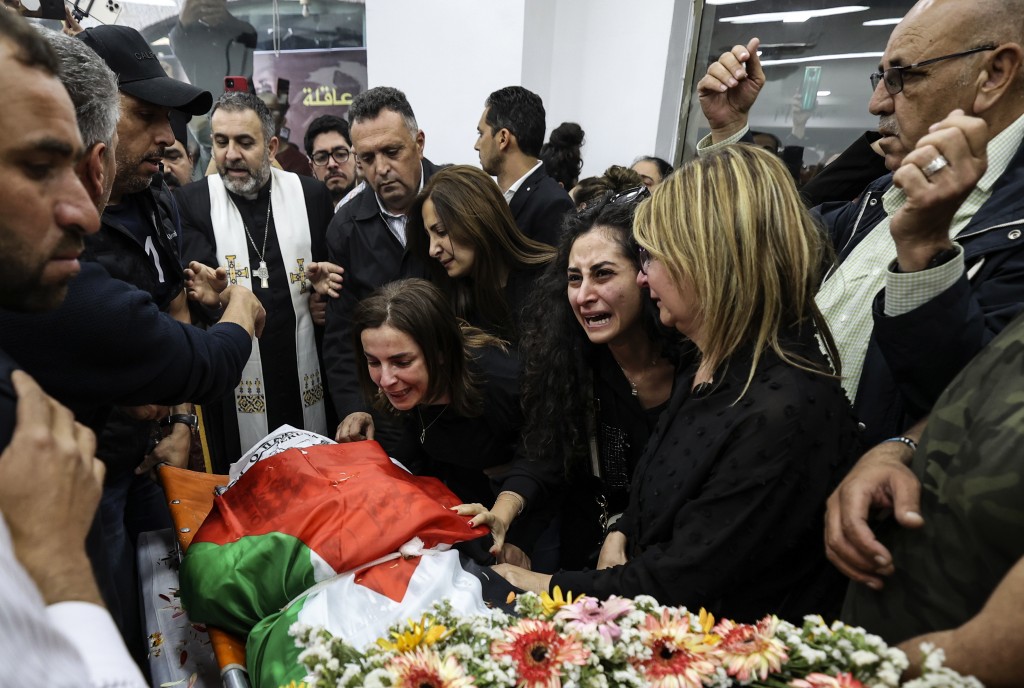 Colleagues and friends mourn as veteran Al Jazeera journalist Shireen Abu Akleh's flag-dropped body is brought to the new organization's offices in Ramallah. Photo: Abbas Momani/AP