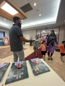 Staff from The Arab American News distributes fliers of the vaccine for kids campagin at the Islamic Institute of Knowledge in Deaborn during Eid Al Adha on June 28.