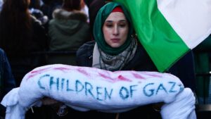 A protester holds a symbolic shrouded, deceased Palestinian child while attending a march calling for a ceasefire in Gaza, in central London on 9 December 2023