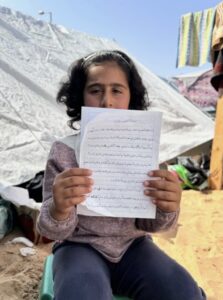 A young girl in Gaza holds up a letter expressing fear about a possible Israeli invasion of Rafah and pleading with President Joe Biden to help end the conflict. – Photo was given to ABC News by Dr. Ahmad