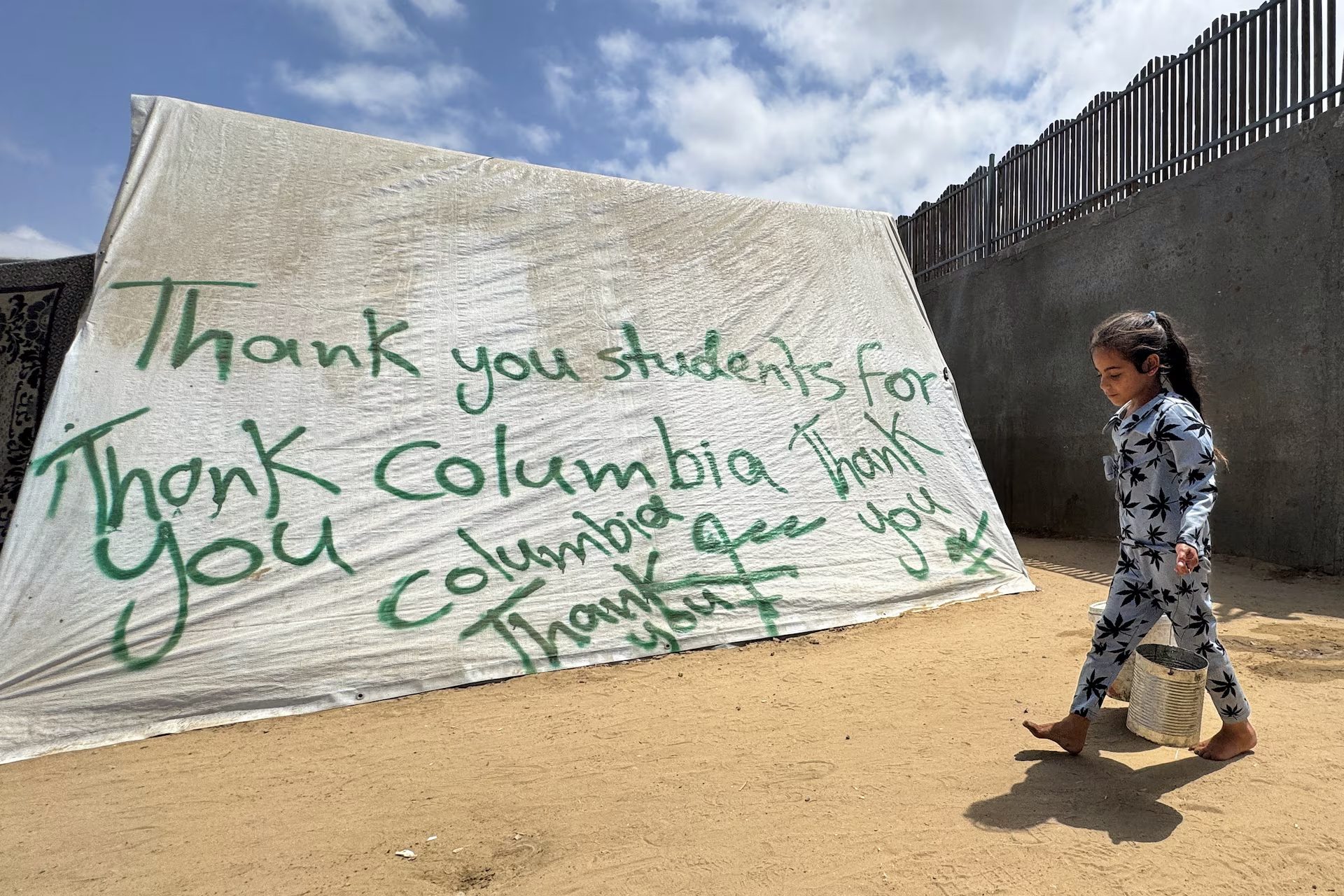 A girl walks next to a tent sprayed with a message in solidarity with pro-Palestinian university students, amid the ongoing conflict between Israel and Palestinians, in Rafah in the southern Gaza Strip, May 2, 2024. REUTERS