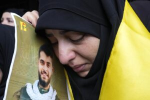 A woman holds a picture of a Hezbollah member who was killed on Wednesday when a handheld device exploded, during his funeral procession in the southern suburbs of Beirut, Thursday, September 19. - Photo by AP