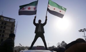 A man holds Syrian opposition flags as he celebrates after Syria's army command notified officers on Sunday that President Bashar al-Assad's 24-year rule has ended, in Aleppo, Syria December 8. 