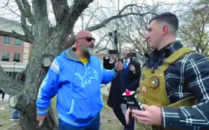 Local activist Abbas Aboukhodr grabs the Qur'an from Lang's hand as he attempts to burn it in an Islamophobic act of intimidation.– Videograb