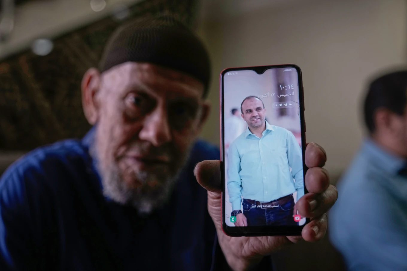 Waleed Husein Ali, holds a picture of his son, Mohammad, 45, who died in Israeli custody at the Kishon detention center, as he sits in the family’s living room in the Nur Shams refugee camp near the West Bank town of Tulkarem, Thursday, Oct. 23, 2025. (AP Photo/Majdi Mohammed)