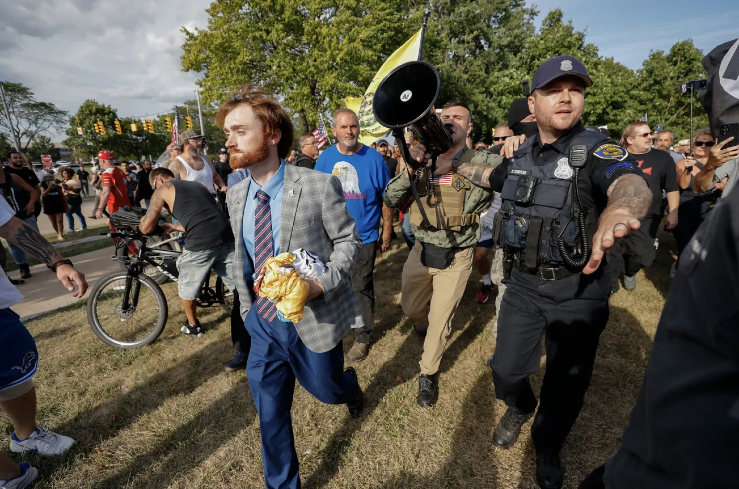 Jake Lang holds a megaphone under police protection during the demonstration heading to the Henry Ford Centennial Library, where the Dearborn City Council was holding its meeting on Tuesday, August 18.
